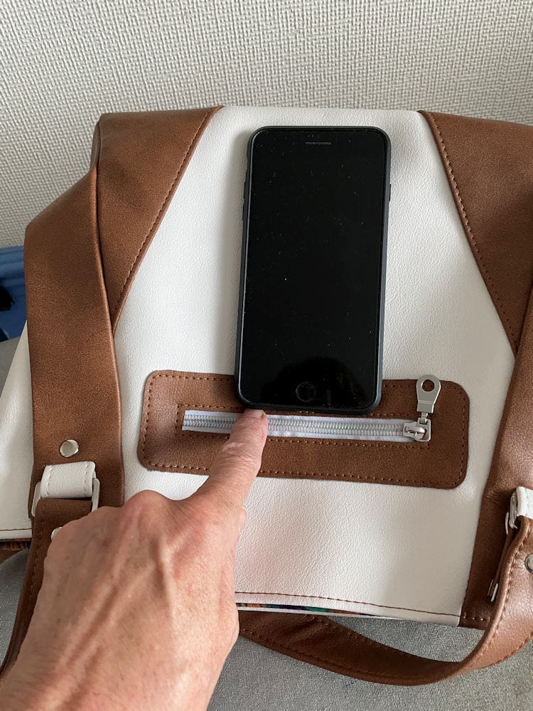 Women's tan and white handbag showing rear pocket will hold mobile phone