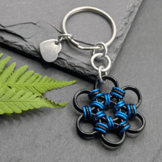 A keyring made into the shape of a flower. Made with larger black rings and smaller blue and black rings