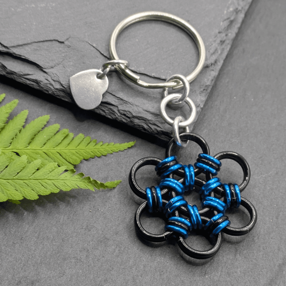 A keyring made into the shape of a flower. Made with larger black rings and smaller blue and black rings