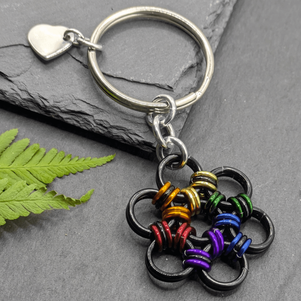 A keyring made into the shape of a flower. Made with larger black rings and smaller rainbow coloured and black rings