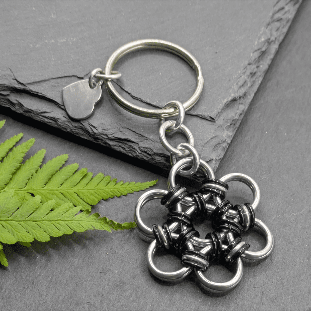 A keyring made into the shape of a flower. Made with larger silver rings and smaller black and silver rings