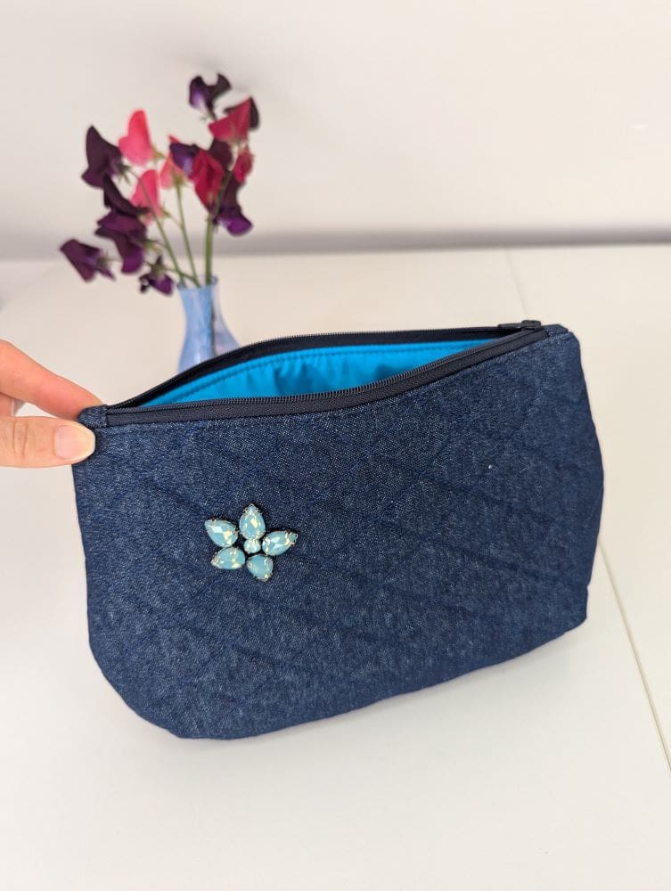 A denim clutch bag with zip opening showing the turquoise lining