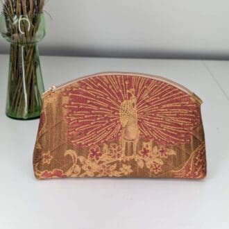 A gold and red, small make-up pouch, handmade with a peacock design