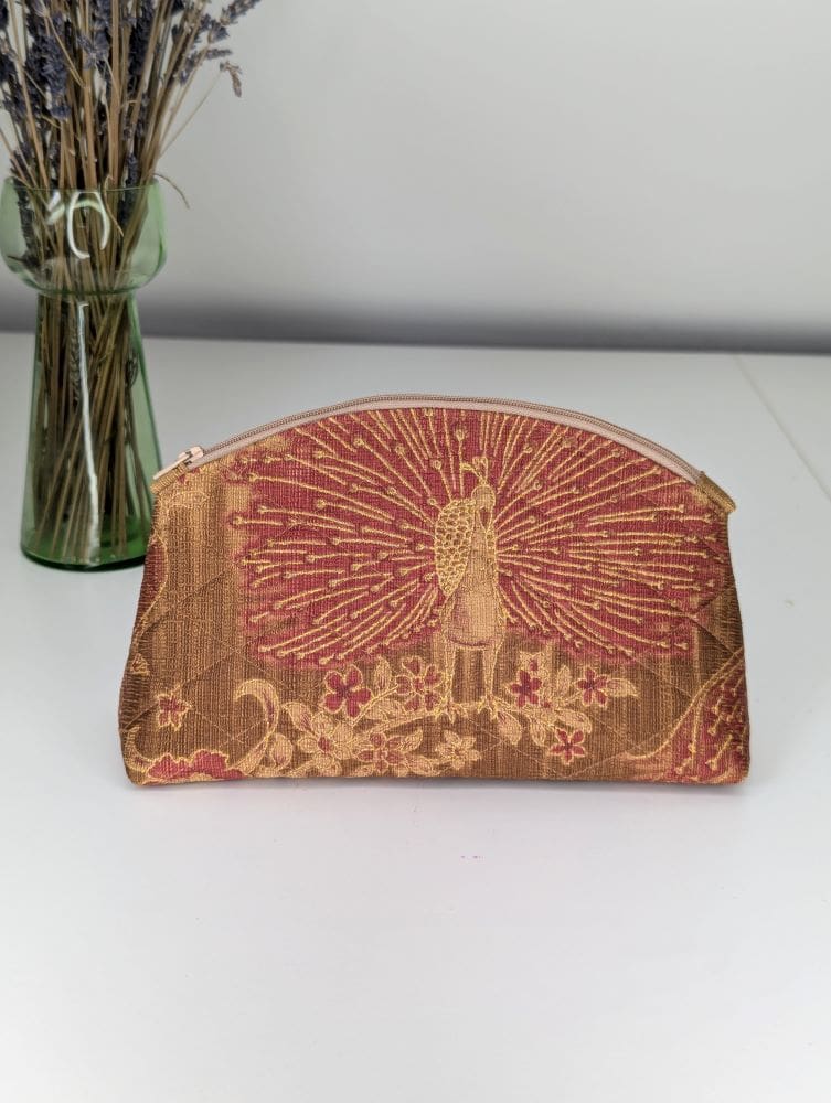 A gold and red, small make-up pouch, handmade with a peacock design