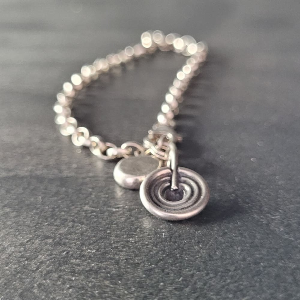 Sterling silver belcher chain bracelet with a charm inspired by ancient rock art known as cup and ring marks.