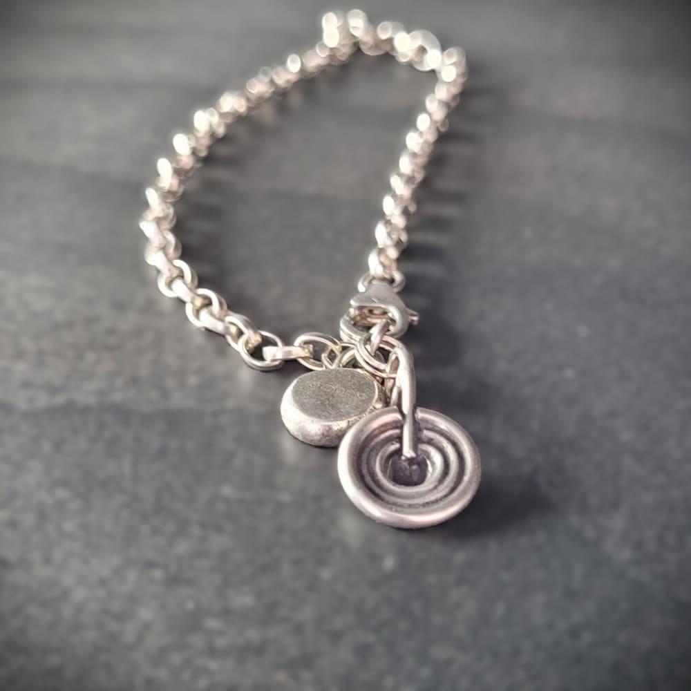 Sterling silver belcher chain bracelet with a charm inspired by ancient rock art known as cup and ring marks.