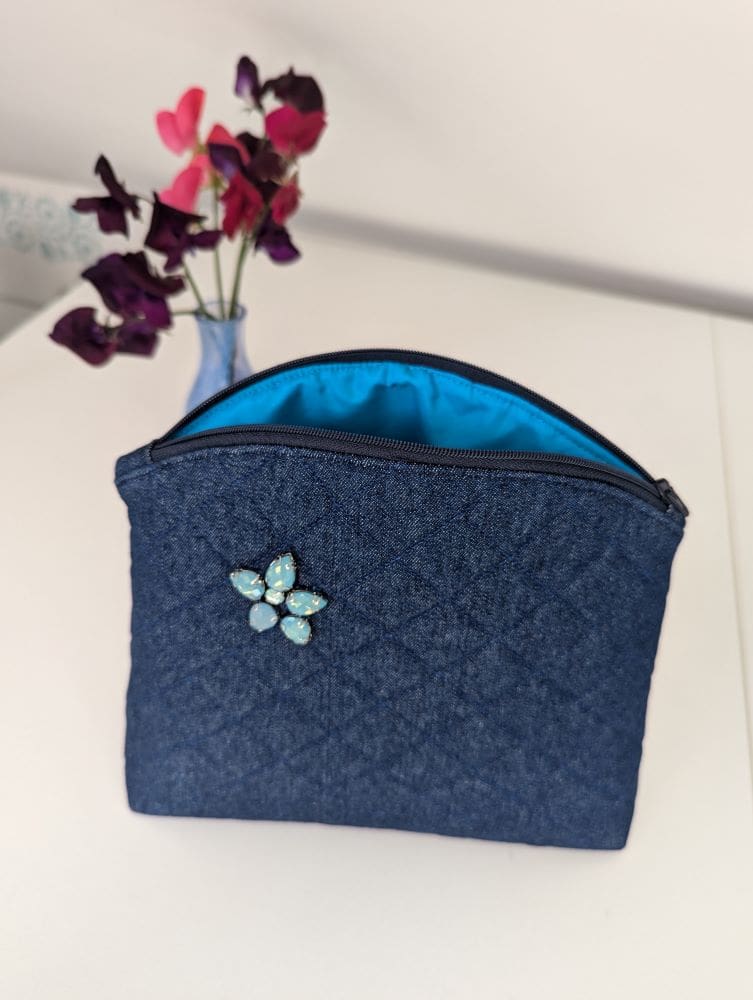 A denim quilted wash bag showing the turquoise lining