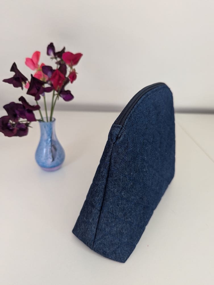 The side view of a quilted denim toiletry bag