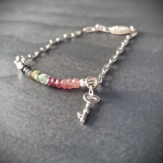 Sterling silver bracelet with a strand of watermelon tourmaline beads and a silver key charm.