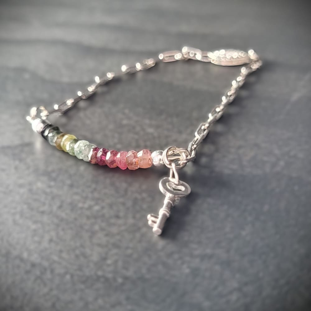 Sterling silver bracelet with a strand of watermelon tourmaline beads and a silver key charm.