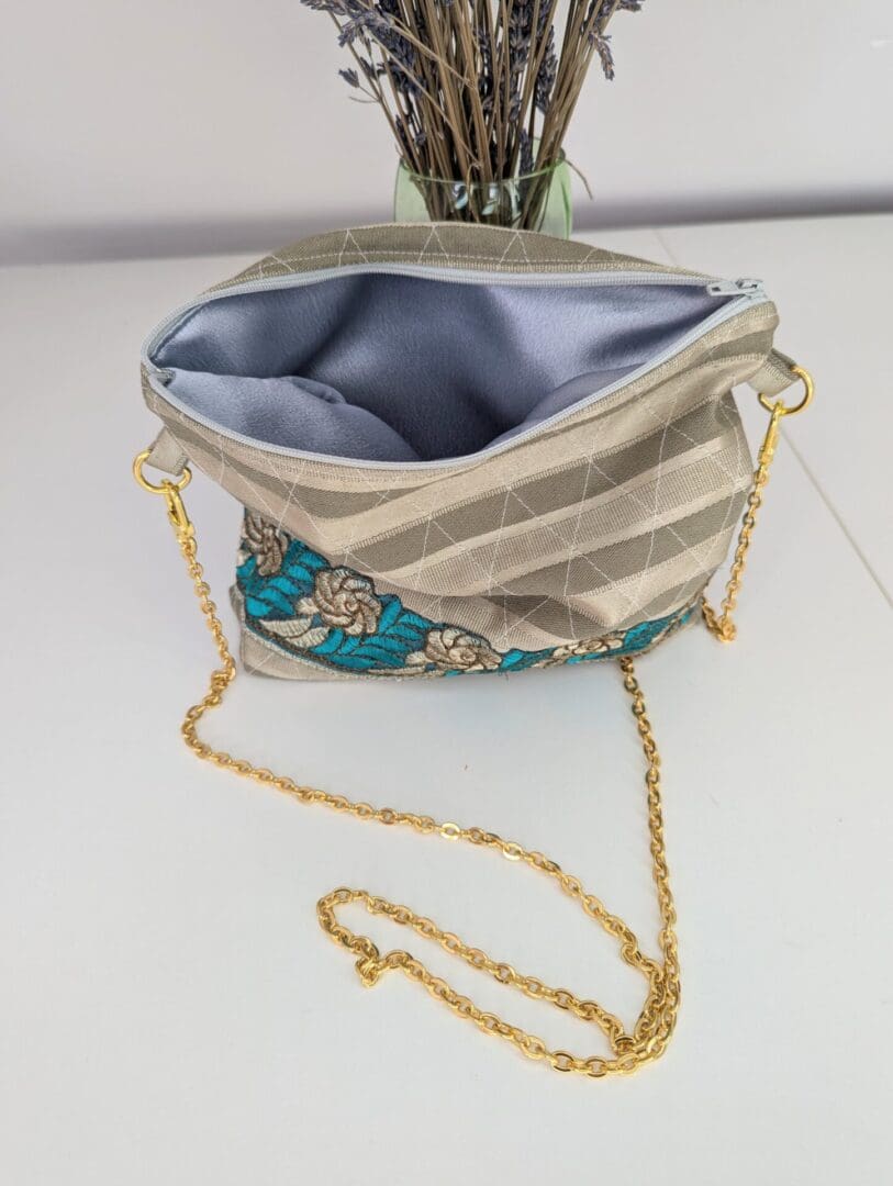 A gold shoulder bag with a matching chain and a silver lining