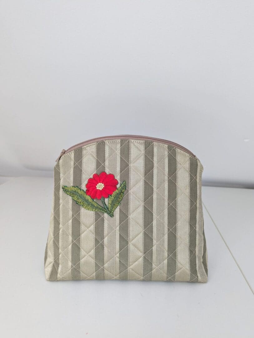 A gold quilted cosmetics bag with a red floral motif