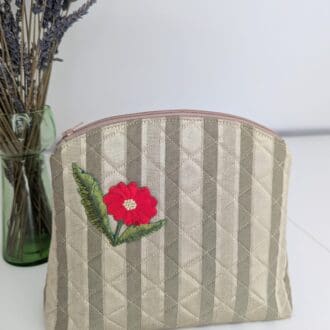 A gold quilted woman's vanity bag with a red floral motif