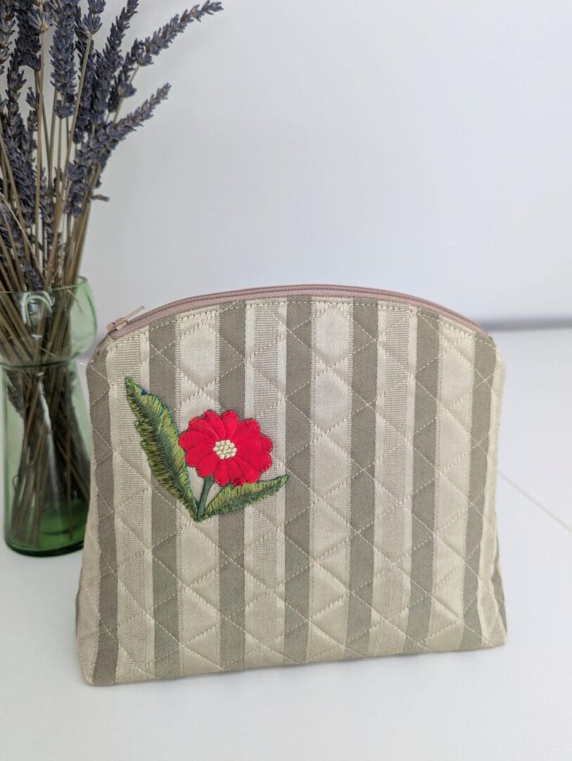 A gold quilted woman's vanity bag with a red floral motif