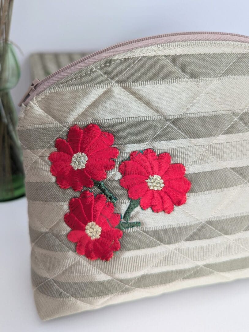 A gold quilted make up bag with red flower motif