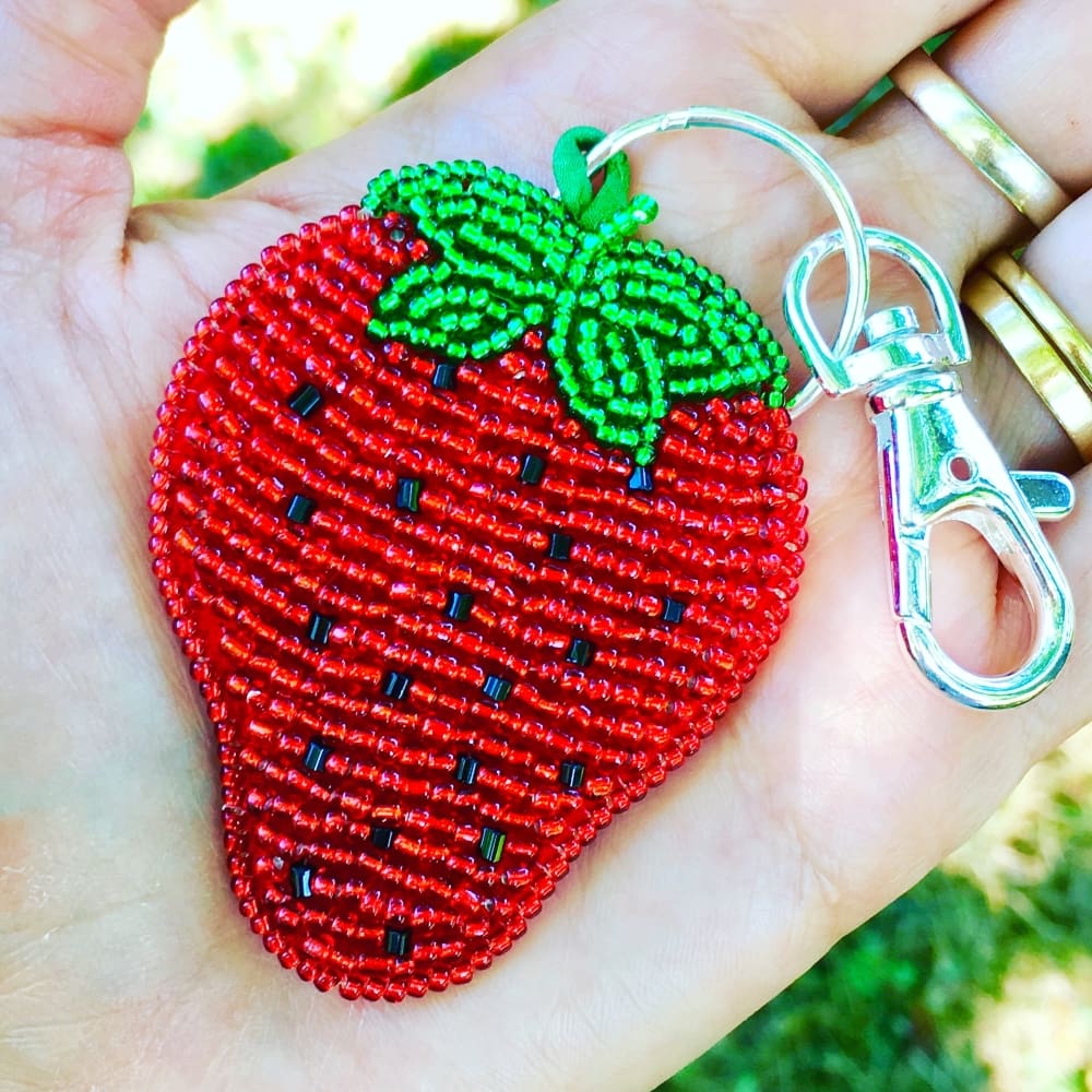 hand beaded strawberry keychain by DewCatDesigns, sitting in the palm of a hand