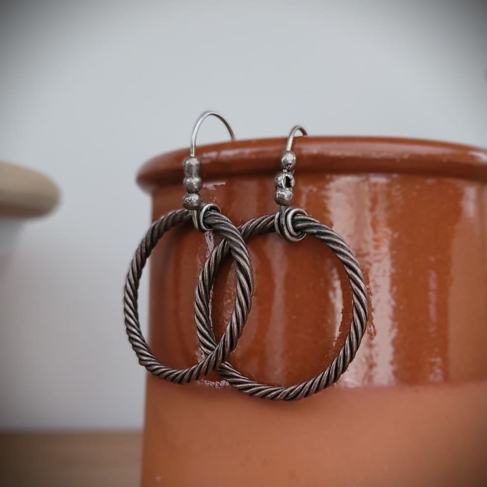 Twisted copper hoop earrings with sterling silver hooks and details in a raw oxidised finish. Part of the Kenaz Collection