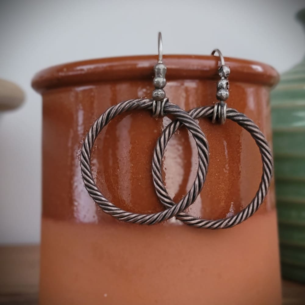 Twisted copper hoop earrings with sterling silver hooks and details in a raw oxidised finish. Part of the Kenaz Collection