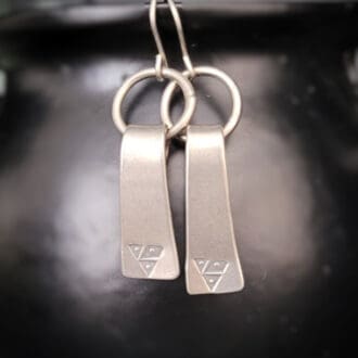 Sterling silver earrings inspired by viking age axe heads. With a matt silver finish they also feature an era appropriate emblem.