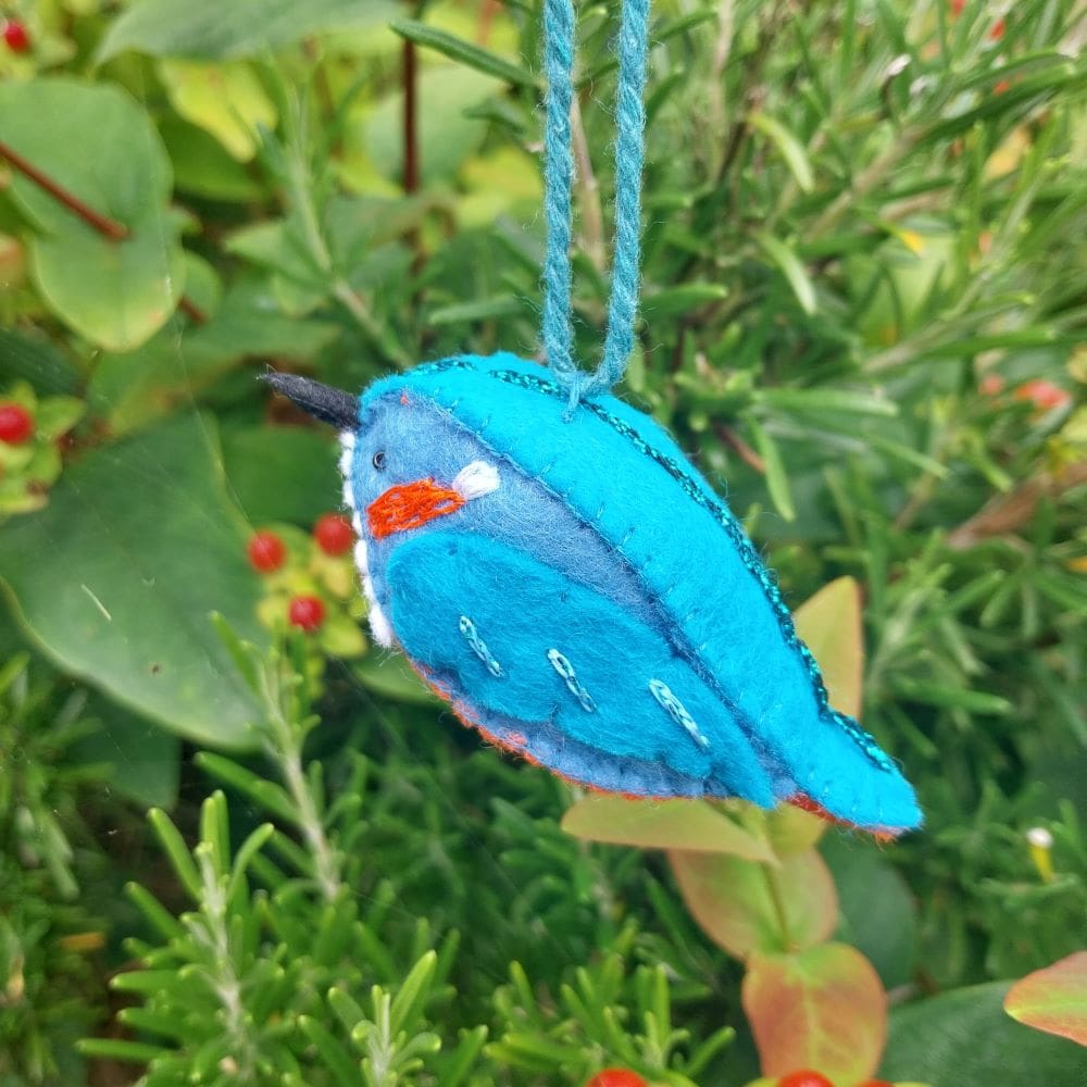 a hand stitched felt Kingfisher by WJ Needlework, gently moving in the wind, catching the light