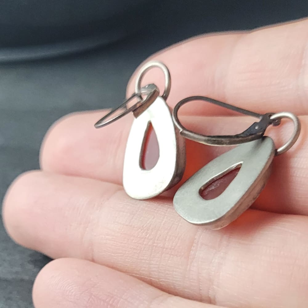 Orange Carnelian Faceted Cabochons in a raw oxidised sterling silver setting. In a teardrop shape with the back cut out to allow light through.