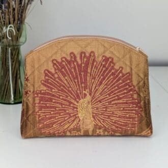 A handmade make-up pouch. Gold in colour and quilted with a red peacock design