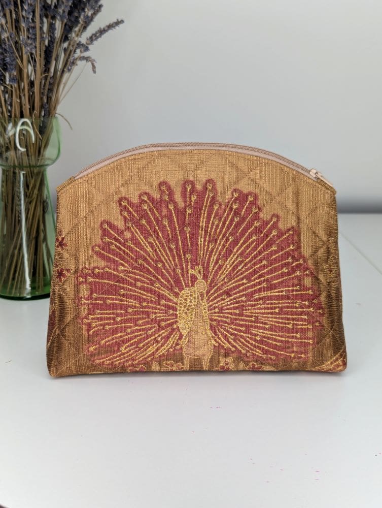 A handmade make-up pouch. Gold in colour and quilted with a red peacock design