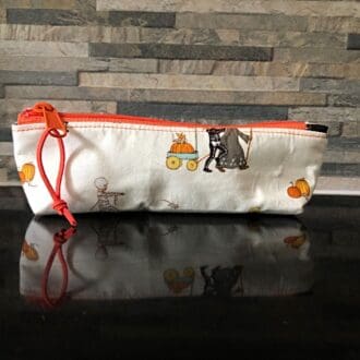 Pencil case or make up bag in cream fabric featuring cute Halloween figures, orange zip and black lining.