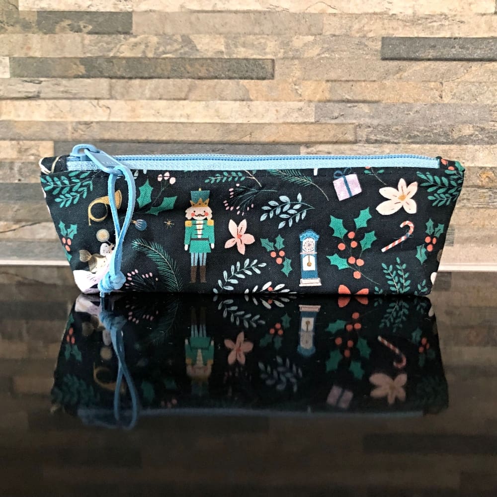 Pencil case or make up bag in dark blue fabric featuring cute figures from the Nutcracker ballet, a pale blue zip and lining.