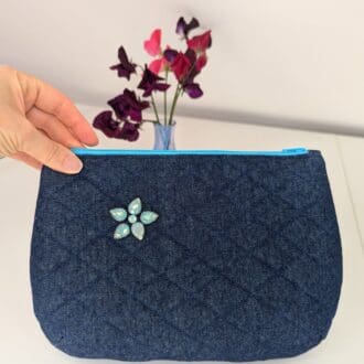 An upcycled denim clutch bag, quilted and embellished with turquoise gemstones