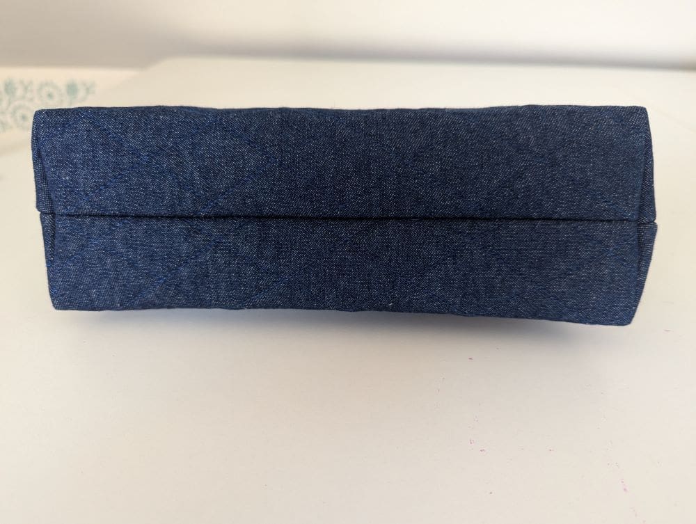 The underside of a small denim make up pouch