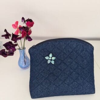 A medium sized quilted denim wash bag with turquoise gemstone embellishment