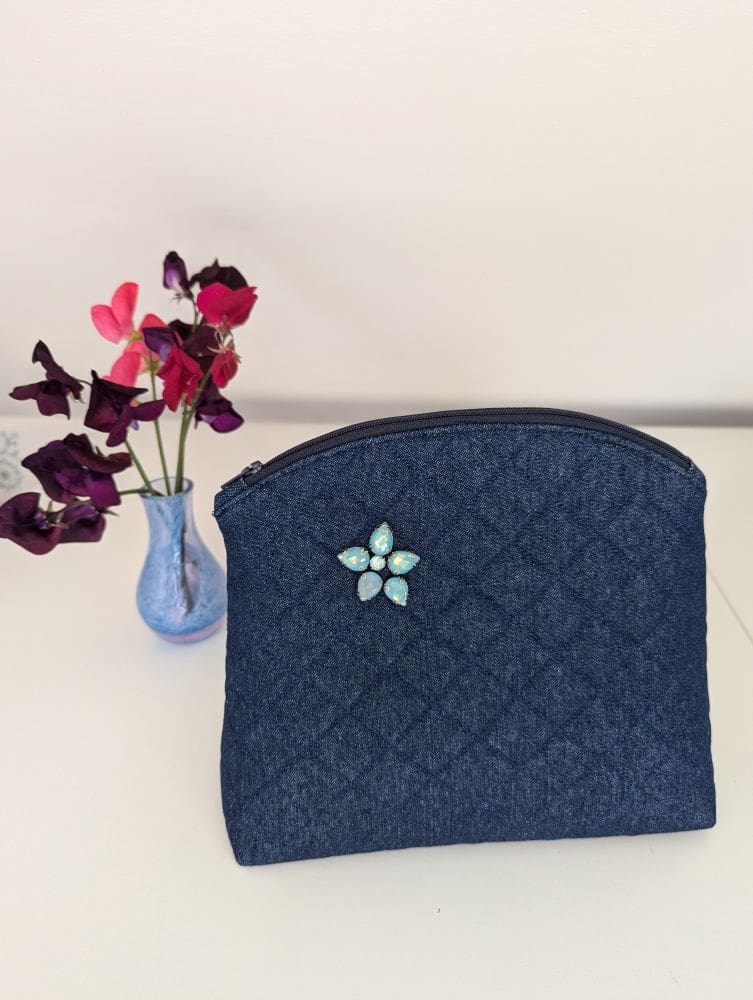 A medium sized quilted denim wash bag with turquoise gemstone embellishment