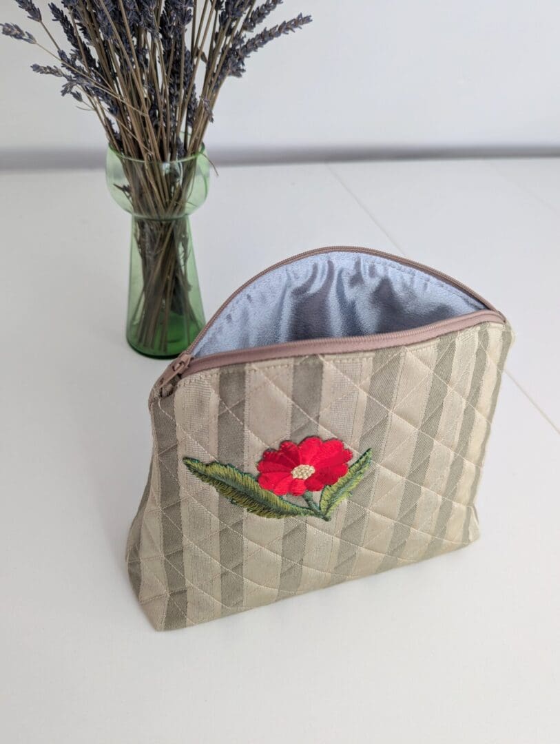 A gold quilted women's cosmetics bag with a red floral motif