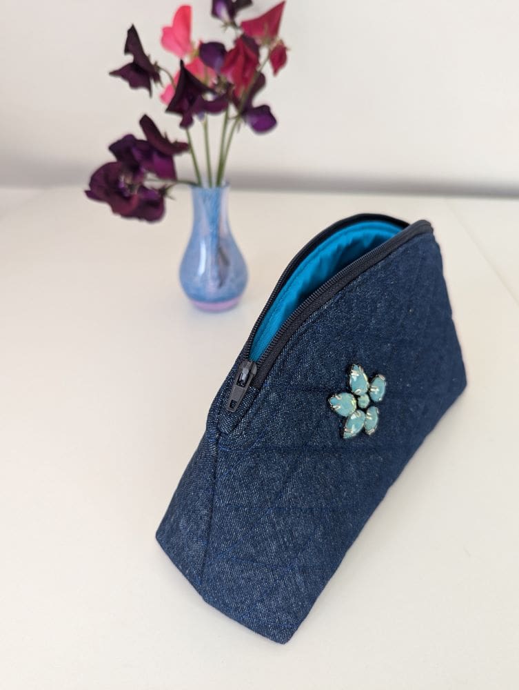 A quilted, denim make up pouch with gemstone embellishment