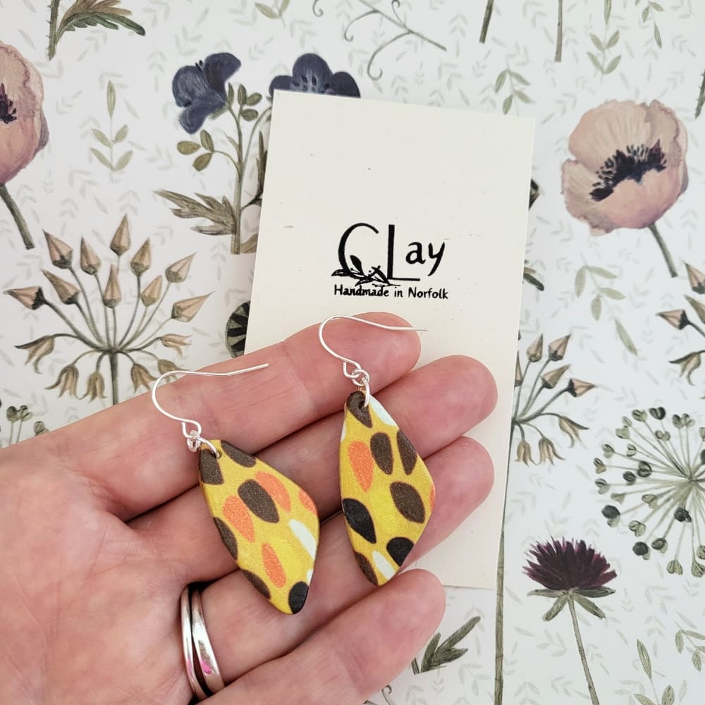 Dangly earrings with a retro style print in warm shades of brown, yellow and orange.