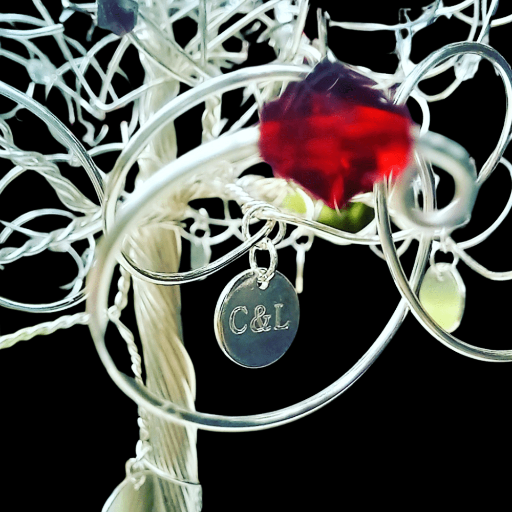 Example of a silver engraved charm, wired onto a silver wire tree with a ruby crystal in the foreground.