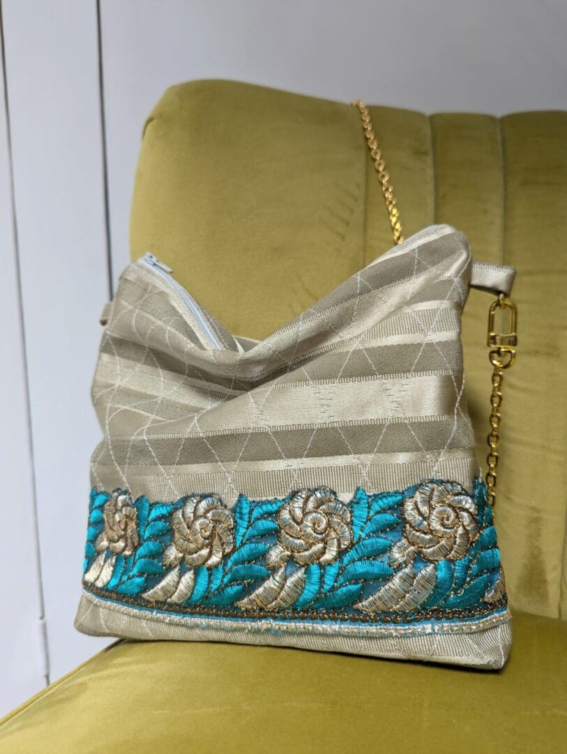 A gold evening bag with gold and turquoise trim and a gold chain