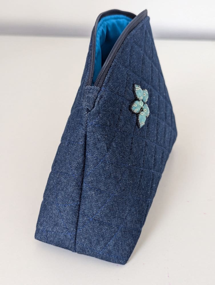 The side view of a medium sized denim make up bag