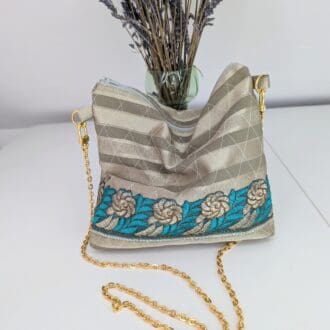 A small, gold, slouchy evening bag with a gold coloured copper chain