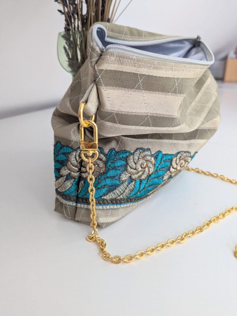 A small gold shoulder bag with a gold coloured, copper chain