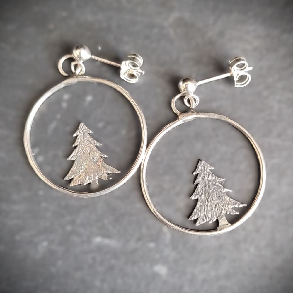 Silver hoop earrings with pine tree.