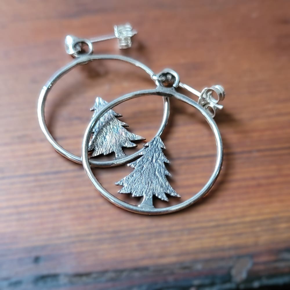 Silver hoop earrings with pine tree.