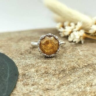 Handcrafted recycled sterling silver floral bezel keepsake ring with amber coloured resin including ashes displayed on stone