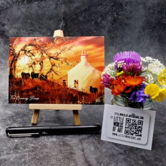 Image titled The Evening Sheep showing an A6 size greetings card, blank inside, on a small easel depicting a view of sheep in the croft garden on a warm summers evening during a vivid golden sunset.