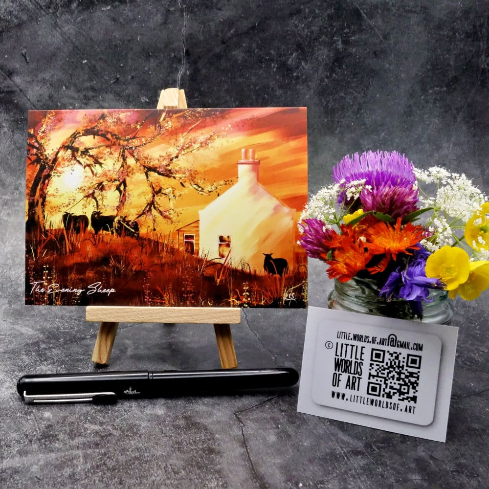 Image titled The Evening Sheep showing an A6 size greetings card, blank inside, on a small easel depicting a view of sheep in the croft garden on a warm summers evening during a vivid golden sunset.