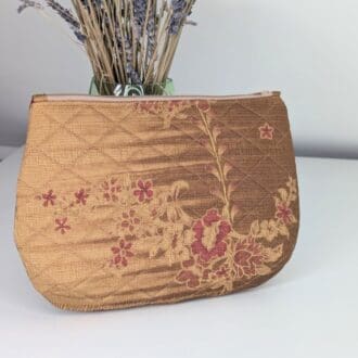 A gold coloured, floral clutch bag with zip fastening, lined in a dep red pleated satin