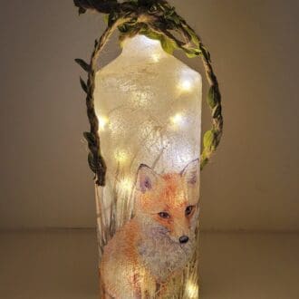 Lit up Square glass bottle with fox detail and green leafy jute twine around the neck. Cork LED lights