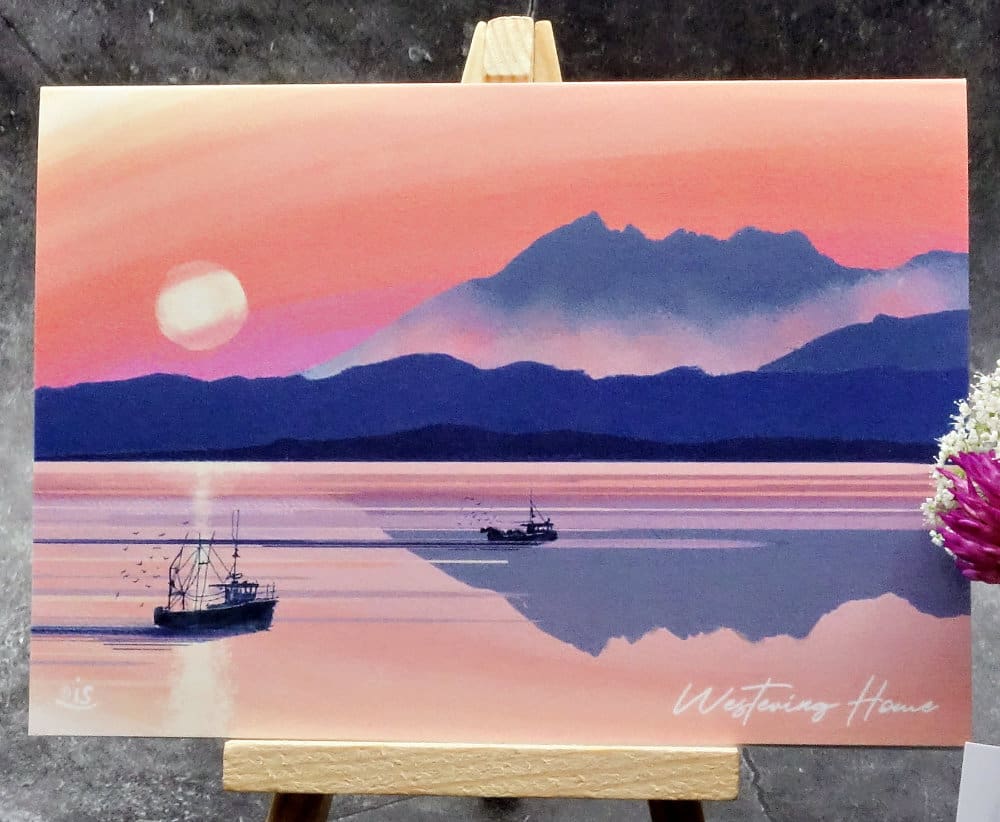 Larger image titled Westering Home showing an A6 size greetings card, blank inside, on a small easel depicting a sunset view towards the Cuillin's over the sea to Skye as the song goes.