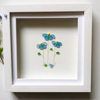 framed picture of forget me not flowers made with Cornish sea glass set in a 24cm square frame